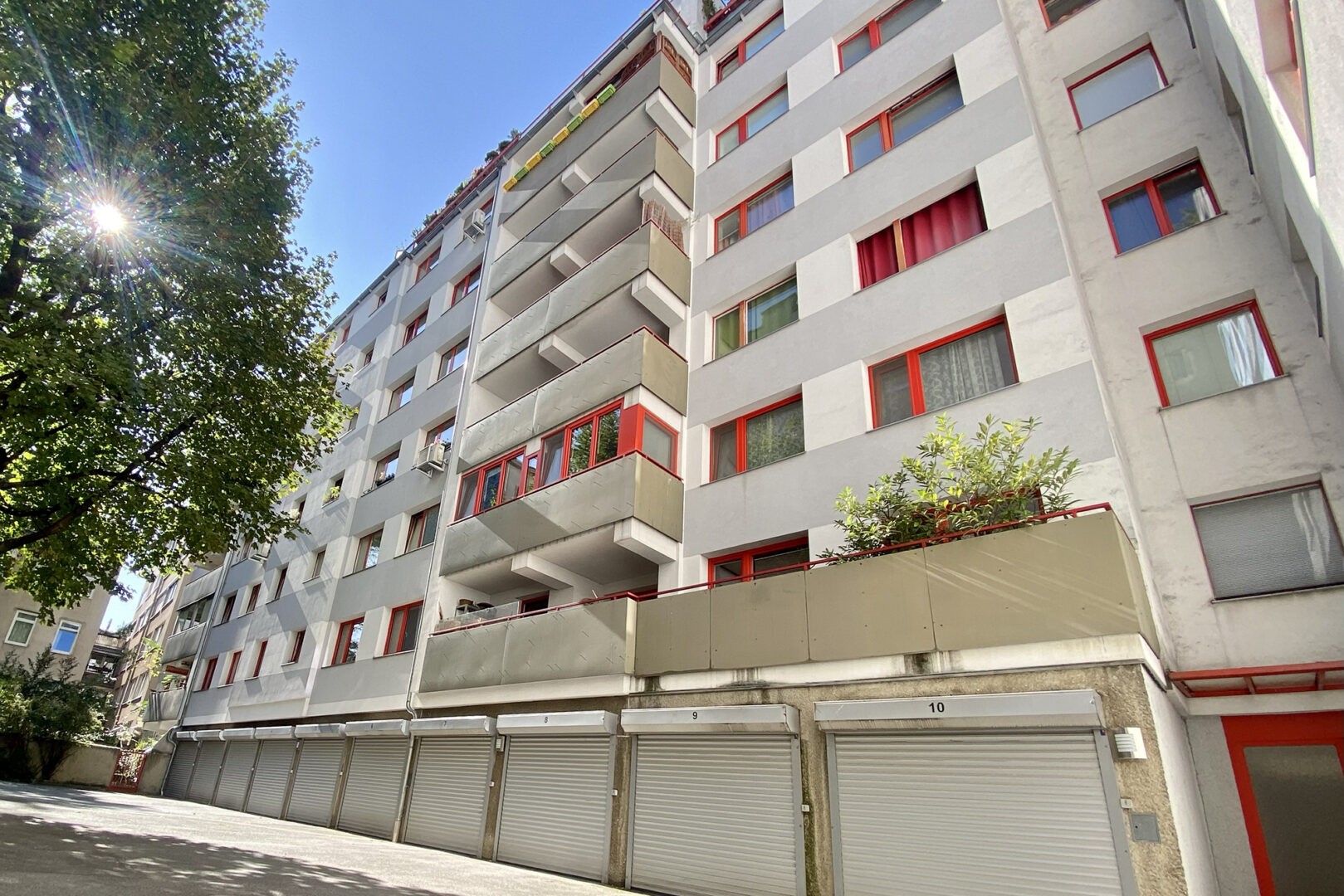 Immobilienverwaltung mit Rubinus, zu sehen ein Wohnhaus aus Beton mit roten Fenstern und Türen.