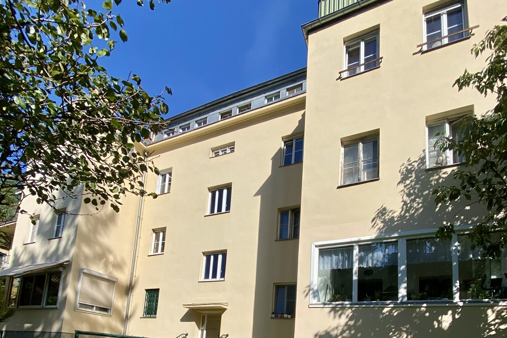 Ein Wohnhaus mit Bäumen umgeben in einer urbanen Lage.