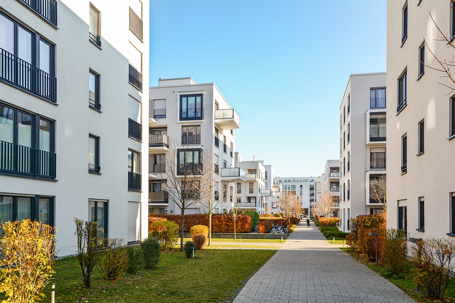 Moderne Wohnbausiedlung, Wohnung mit Balkon und Grünflächen davor in einem urbanen Umfeld.